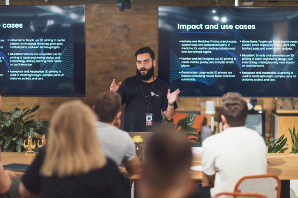 Professional speaker discusses 3D printing applications with attentive audience in tech seminar.